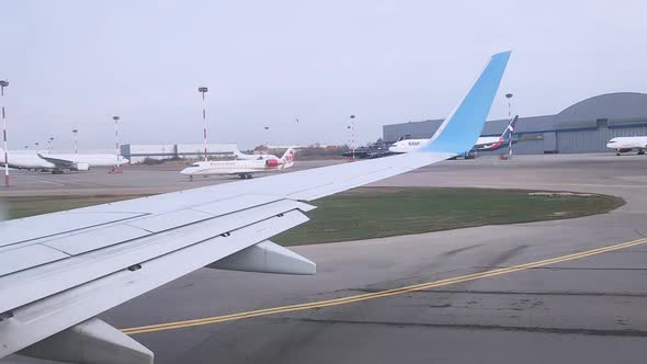 View of the Wing of the Plane That is Going to the Runway and the Airport From the Cabin of the