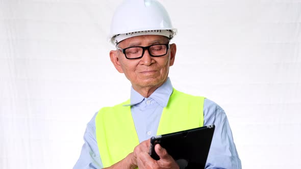 Senior architect engineering builder wearing safety vest and helmet looks at work .