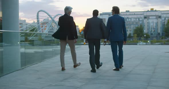 Follow Shot of Three Diverse Business People Walking and Talking on Street