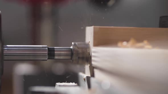 The Drilling Machine Makes a Hole in a Wooden Board