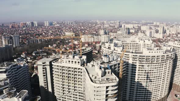 Aerial Shot of the Highrise Building in the Process of Construction with Working Crane in the City