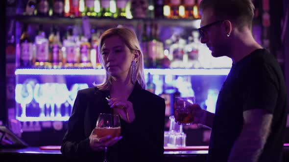 Handsome Bearded Guy in Glasses with an Alcoholic Cocktail Comes Up To a Girl