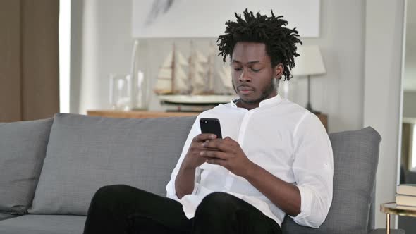Young African Man Using Smartphone at Home 