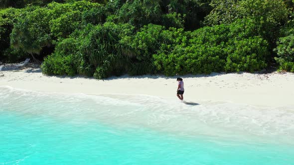 Single female relaxing on tranquil lagoon beach lifestyle by aqua blue water and white sandy backgro