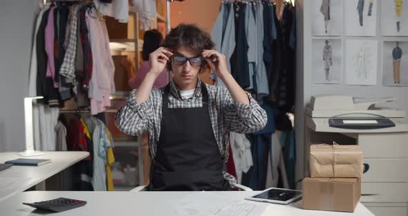 Portrait of Young Male Designer in Glasses Sitting at Desk in Warehouse