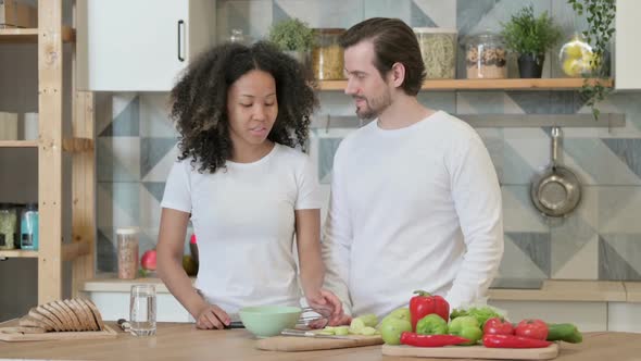 Serious Mixed Race Couple Talking While Standing in Kitchen