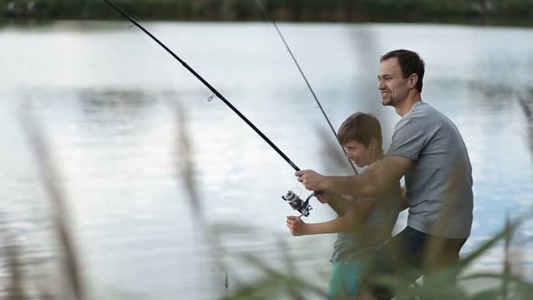 Excited Father and Son Pulling Fish Out From Lake