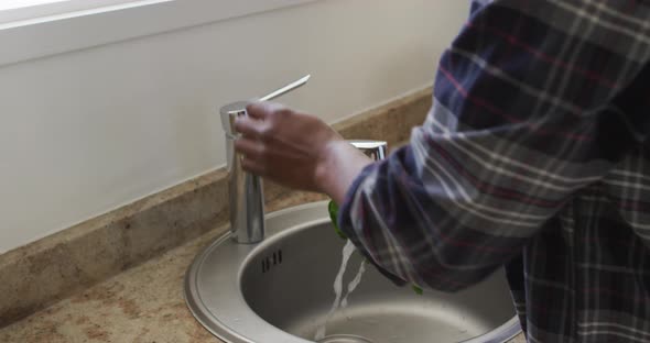 African American senior man stading in a ktichen, washing a cabbage, social distancing and self isol