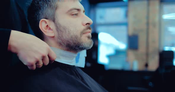 Hairdresser Fixes the Collar to the Client Around His Neck Before Cutting