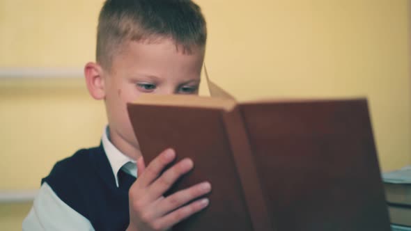 Sad Boy Turns Pages of Textbook Preparing for Exams at Home