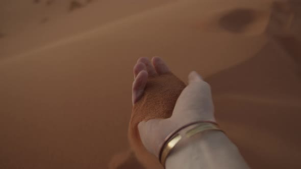 Closeup of Fine Sand Falling From Male Hand and Drifting in Wind