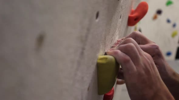 Close-up of a mans hands has he climbs in an indoor climbing gym.