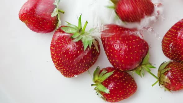 Strawberries Fall From Above Into the Water on a White Background Hit Each Other Swim and Move