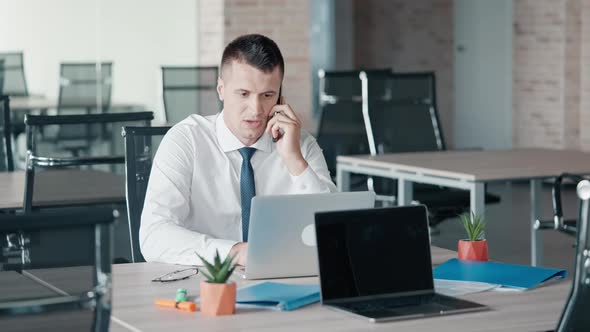 Manager Talking with Client By Phone Sitting at Workspace