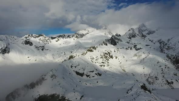 Flying Over Snow-capped Mountains in Clouds