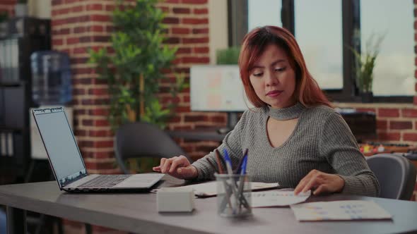 Business Woman Analyzing Sales Statistics on Papers in Startup Office