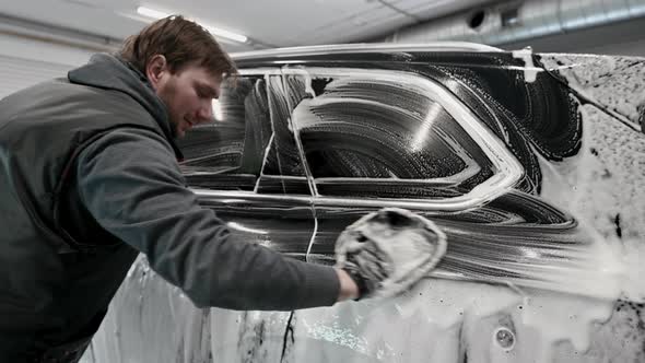 A Man Making Manual Car Wash on a Black Car with Special Cleaning Glove