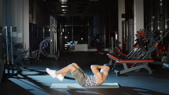 Sportsman Doing Twist Sit Ups Abdominal Crunches Lying on a Floor Mat in Gym