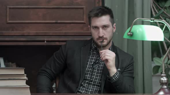 Handsome Young Man Holding Glasses and Looking Into the Camera