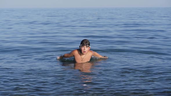 Darkhaired Tanned Boy Splashes Seawater