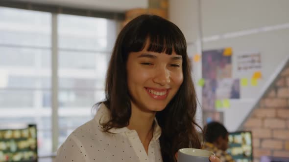 Businesswoman smiling and looking at camera while holding coffee