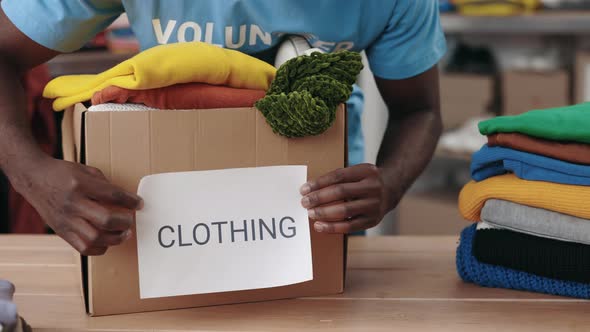 Multiracial Male Volunteer Putting Paper with Clothing Word at the Cupboard Box with Donation