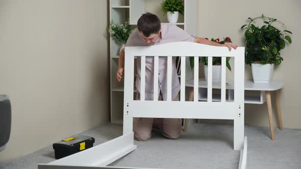 A Man Assembles the Body of a Children's Wooden Bed