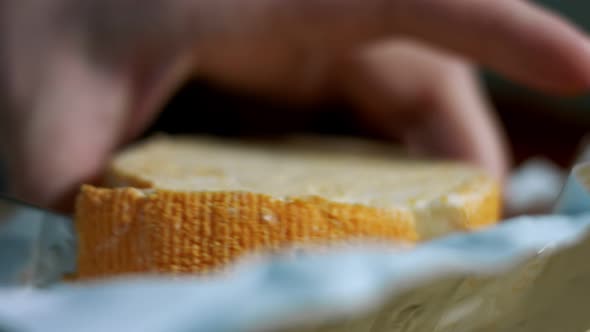 Closeup of Hand Cutting French Cheese Marquis Castello