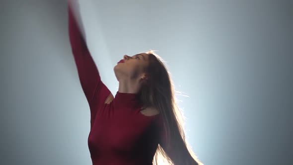 Guy and a Girl Are Dancing with Supports on the Background of a Spotlight in a Dark Studio. Slow