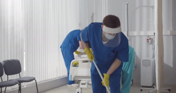 Janitors in Scrubs and Safety Mask Cleaning Hospital Room