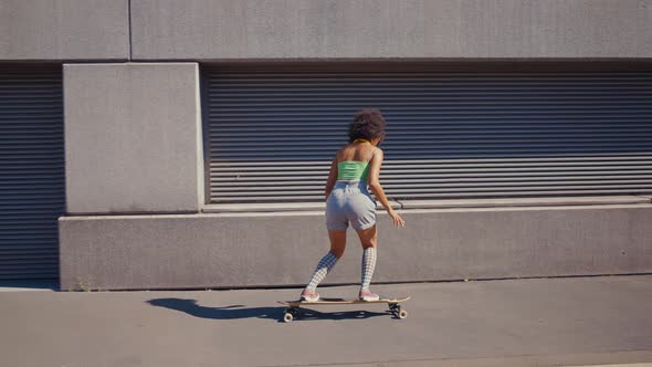 Beautiful young woman cruising around the city with her longboard.