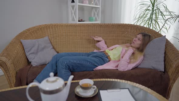 Wide Shot Worried Young Woman Talking Gesturing Lying on Couch in Psychological Office