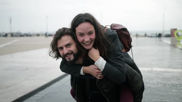 Happy Handsome Man Holding Joyful Girlfriend on His Back