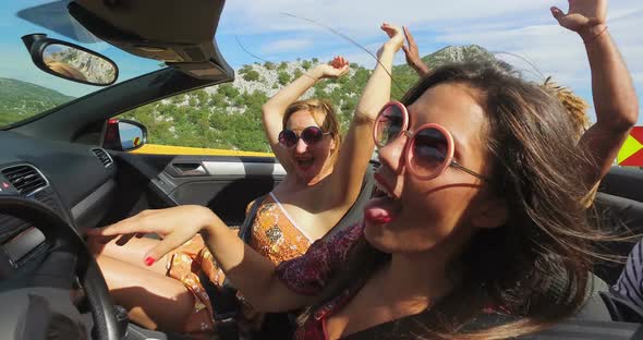 Attractive woman with round frame pink sunglasses driving friends in convertible