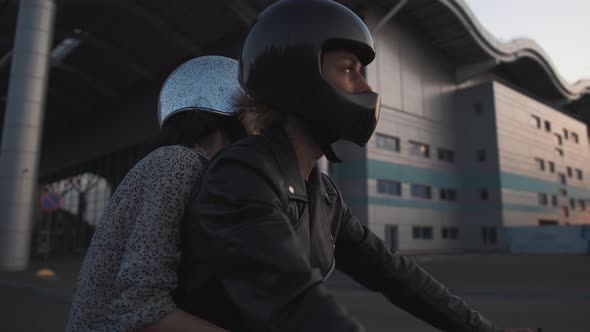 Young Couple in Helmets Riding on Motorcycle in City During Sunset Slow Motion Close Up