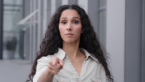 Head Shot Female Millennial 30s Woman with Long Curly Hair Pointing Finger Looking at Camera Making