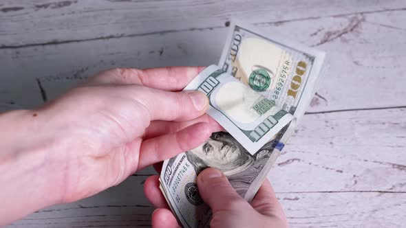 Female Hands are Counting a Stack of 100 Dollar Bills Leafing Through Banknotes