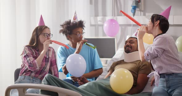 Diverse Young People Celebrating Birthday of Sick Friend in Hospital Ward