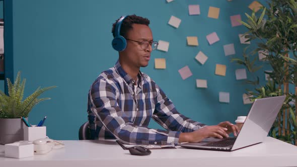 Office Worker Listening to Music and Singing While He Uses Laptop