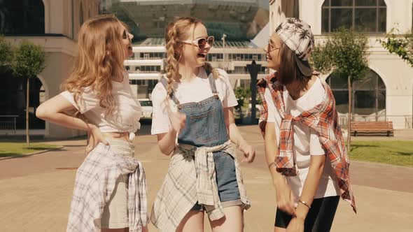 Portrait of three young beautiful smiling hipster female in trendy summer clothes