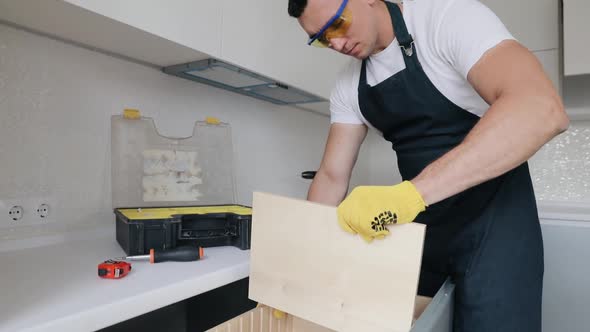 Successful furniture assembly worker adjusting shelf. Finishes his job for cabinet at the kitchen. 