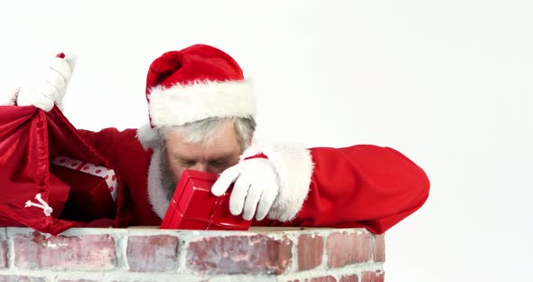 Santa claus placing gift box into a chimney