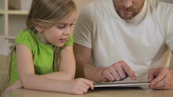 Happy Father and Daughter Enjoying Funny Educational Application on Tablet Pc
