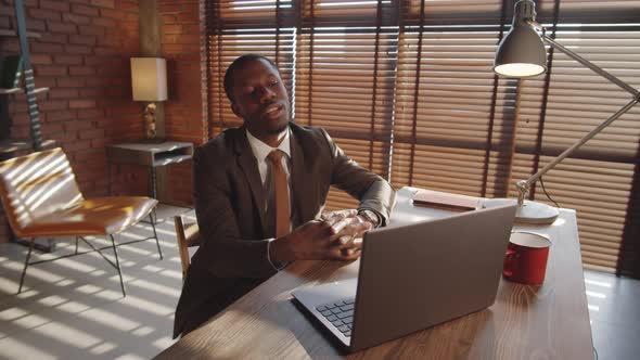 Black Businessman Talking on Web Call on Laptop at Office Workplace