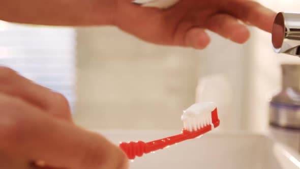 Man putting toothpaste on toothbrush