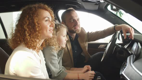 Young Caucasian Couple Sit Inside of New Car in Dealership.