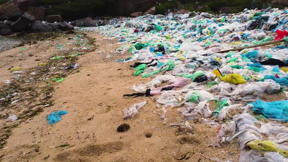 Sandy beach covered in plastic bags, environmental disaster; low aerial