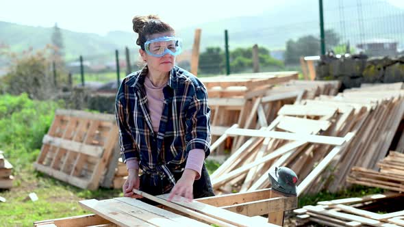 Woman turning over wooden boards in countryside