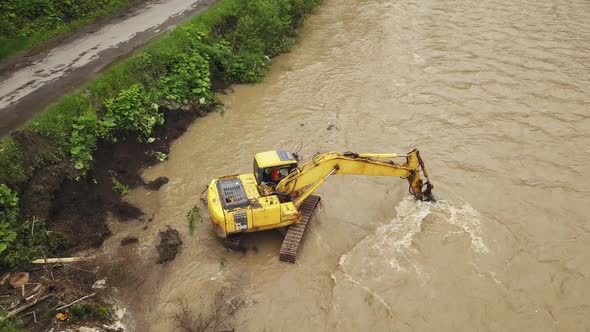 Yellow dredge Excavator working in the mountain river, scooping excavator bucket. Extracting gravel