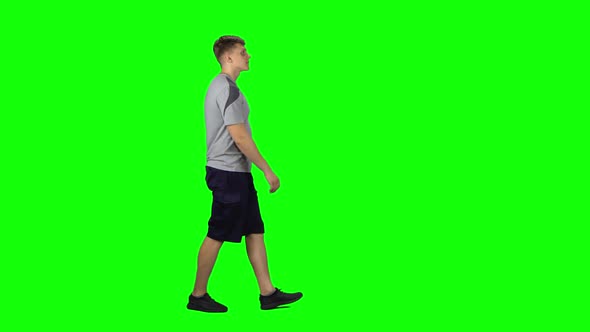 Young Man Walking on a Green Screen. Profile Side View